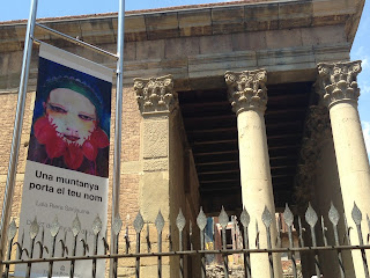 The façade of the Roman Temple in Vic with a poster for Una muntanya porta el teu nom.
